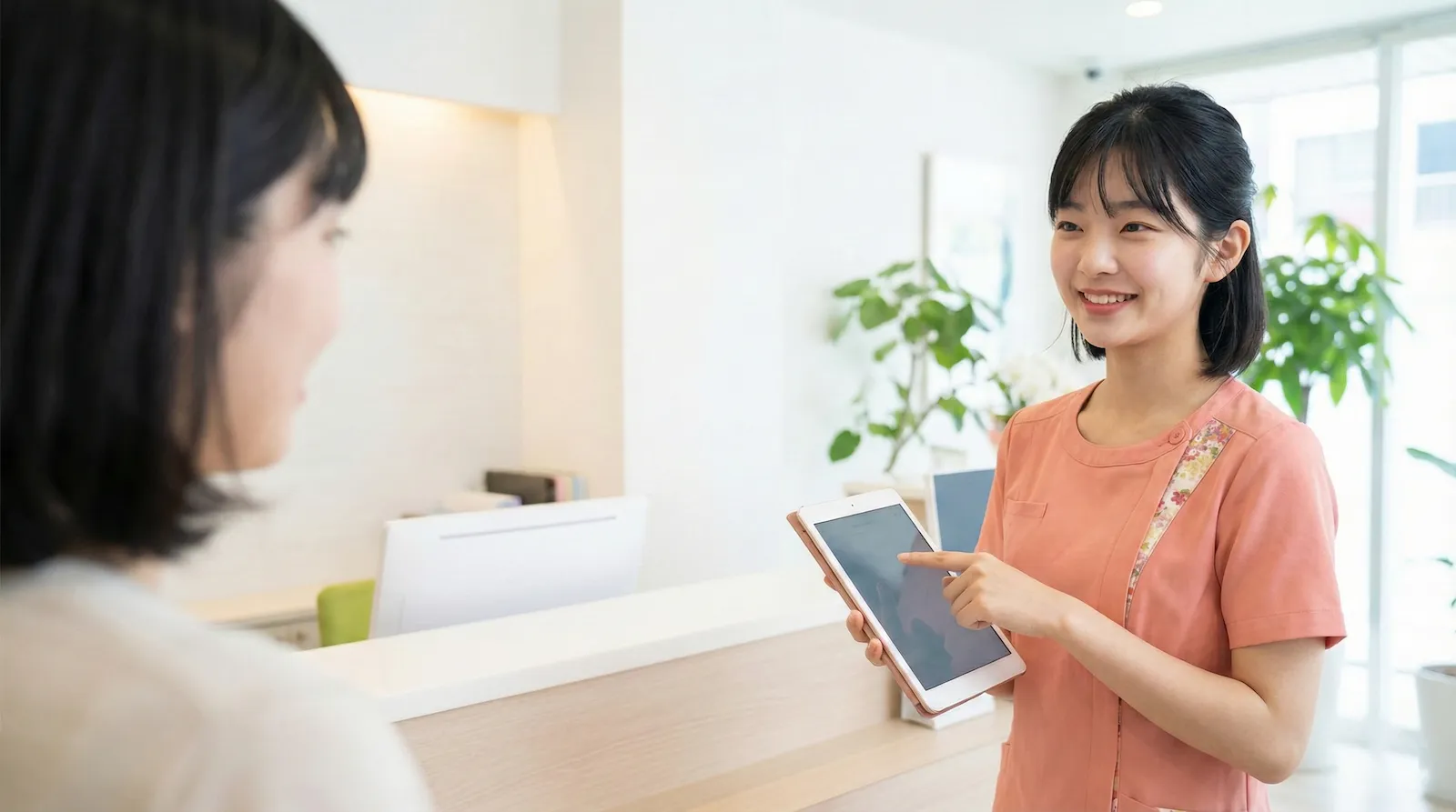 笑顔でタブレットを使い患者さまに説明する歯科衛生士